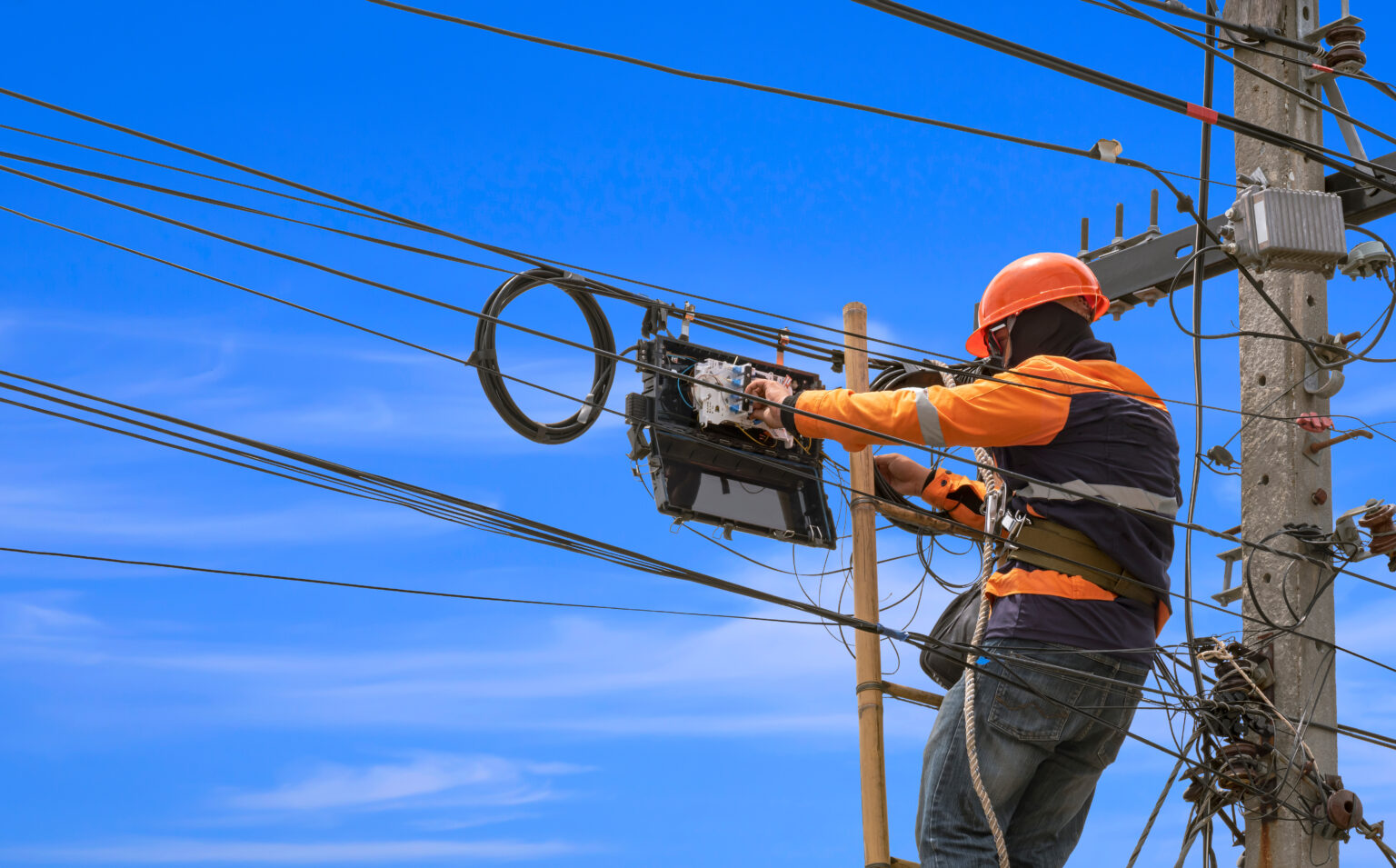 A fiber technician installing aerial fiber cables to a pole.